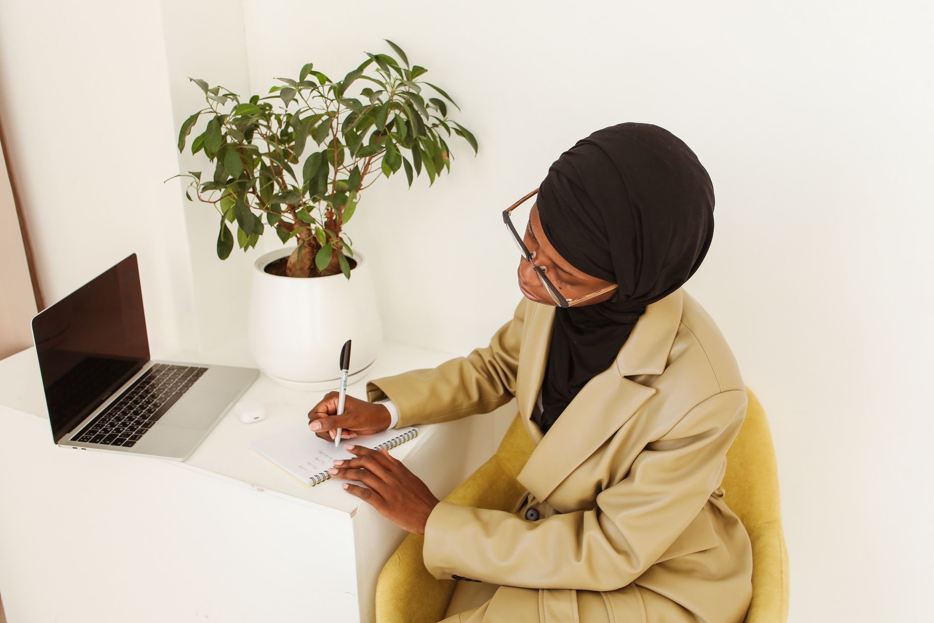 A business owner reflecting and writing at their desk