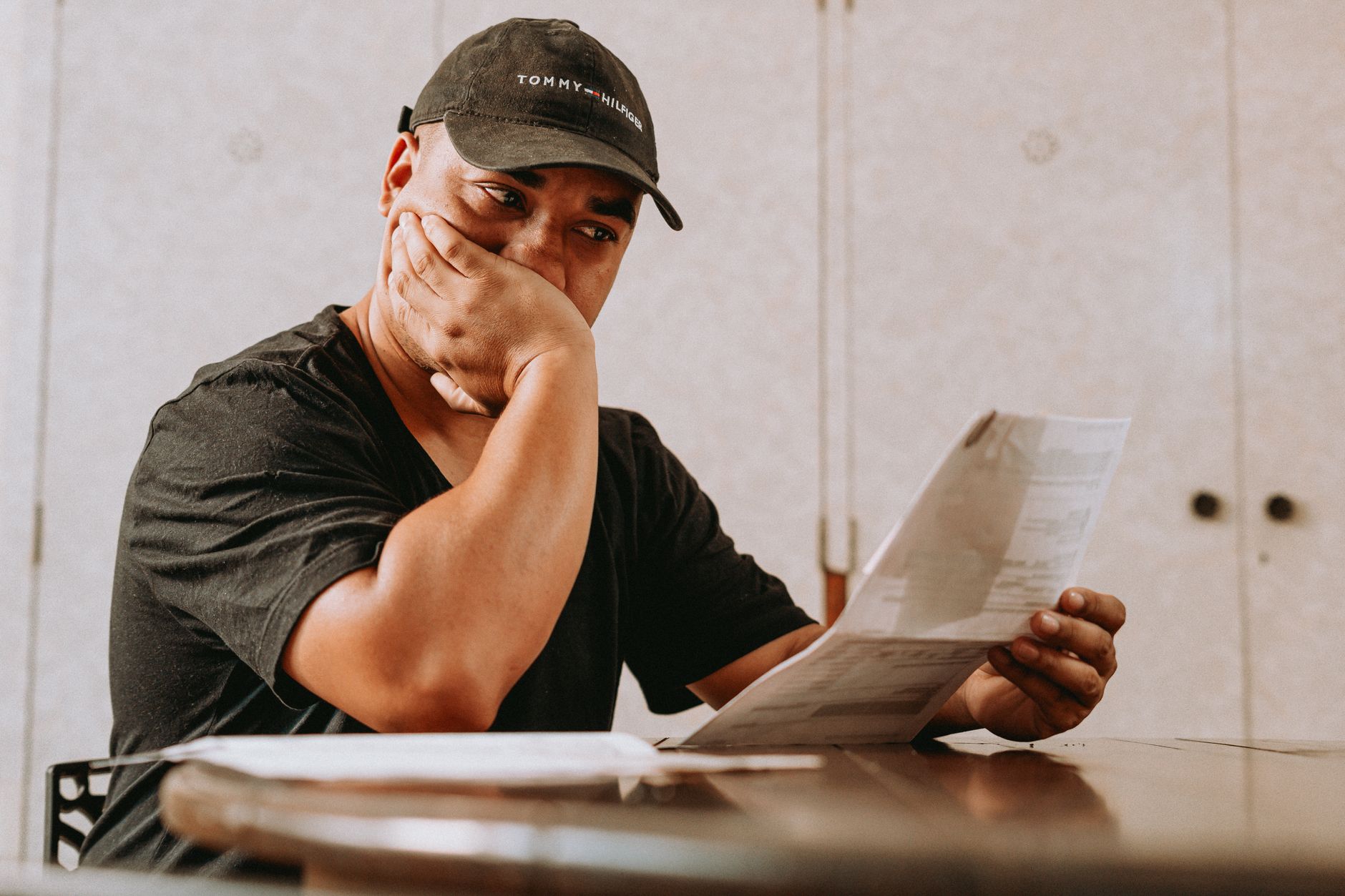 A young adult reading correspondence with a wary expression