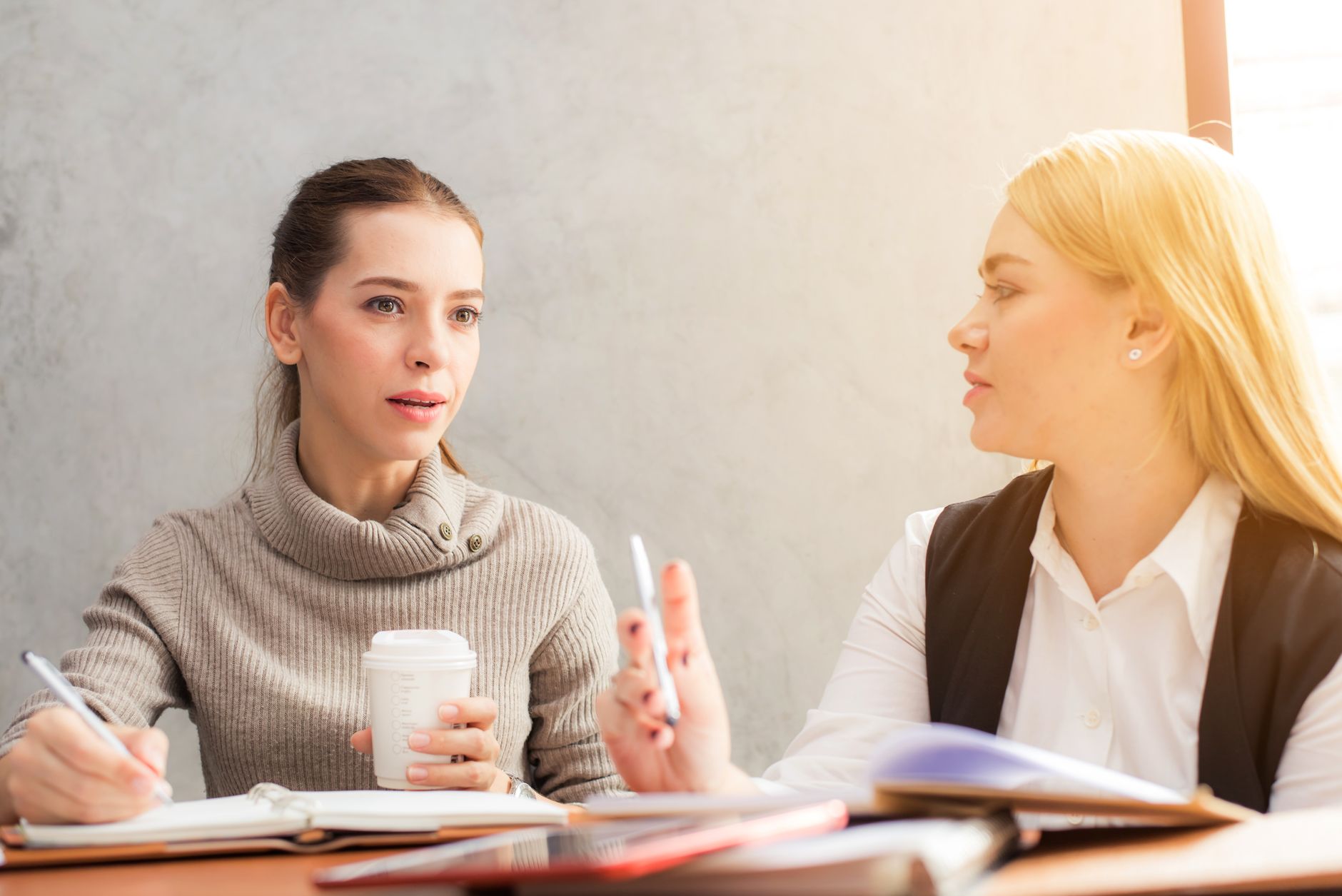 Two colleagues discussing how to word an invitation for different audiences