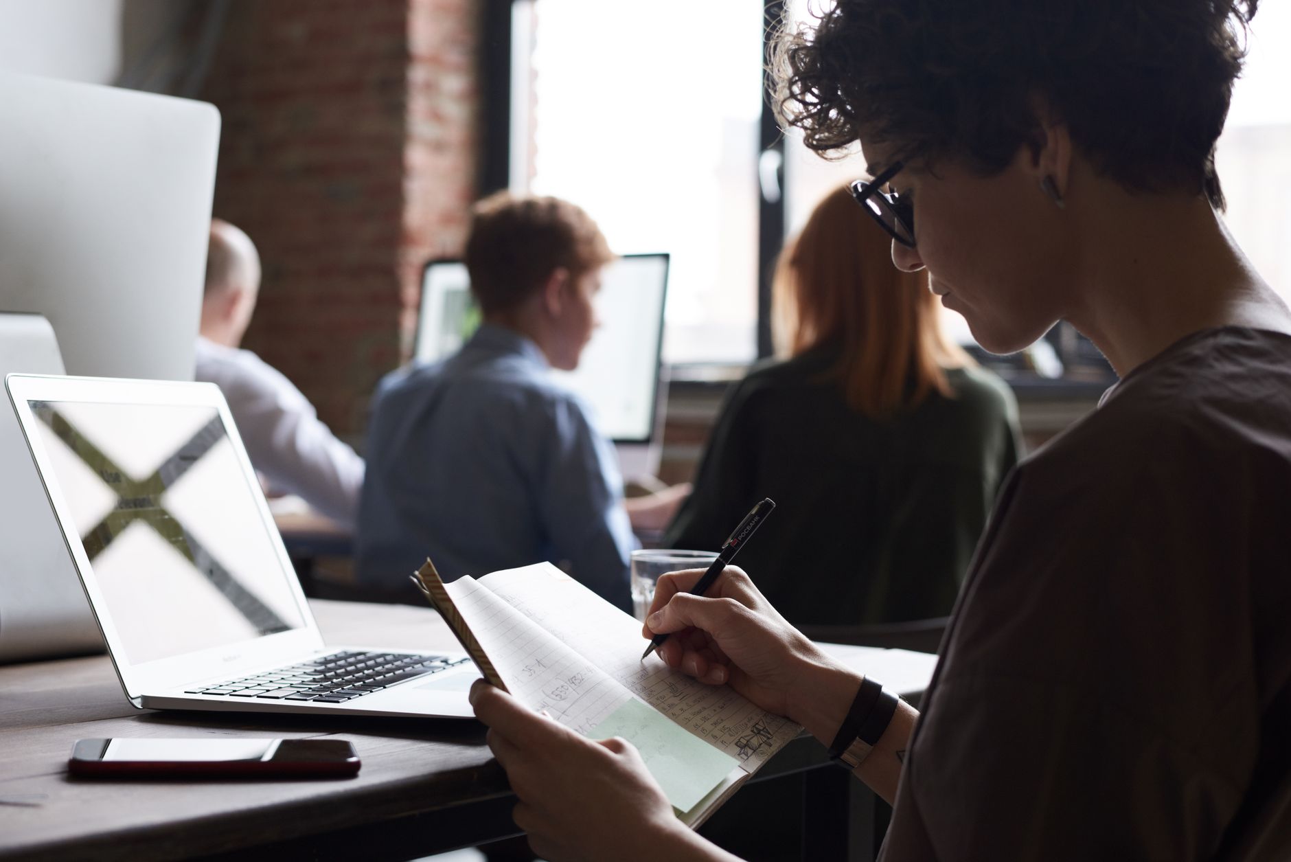 A business owner writing out a simple marketing plan in a notebook