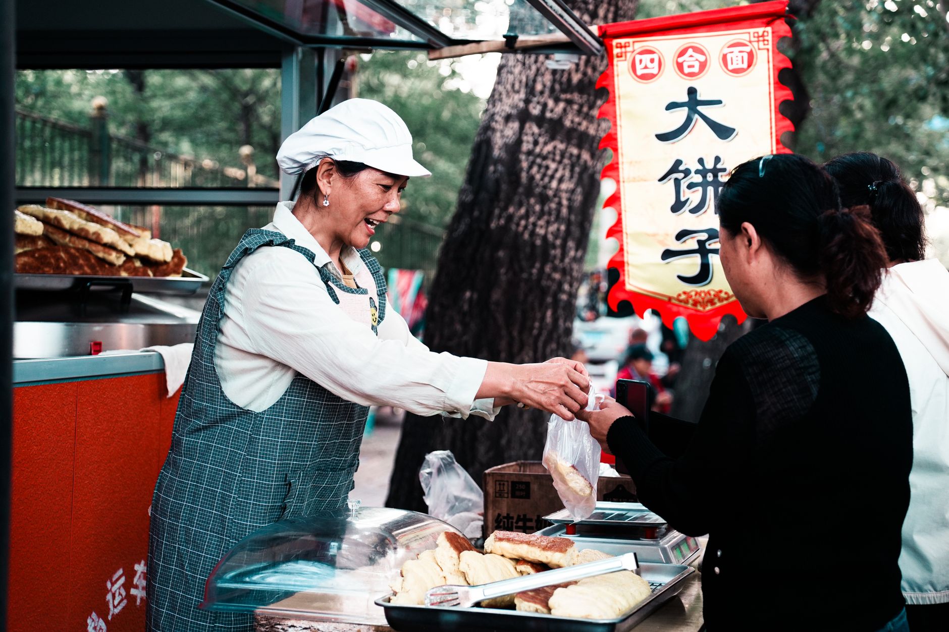 A market trader with a distinctive hand-painted sign serving a customer