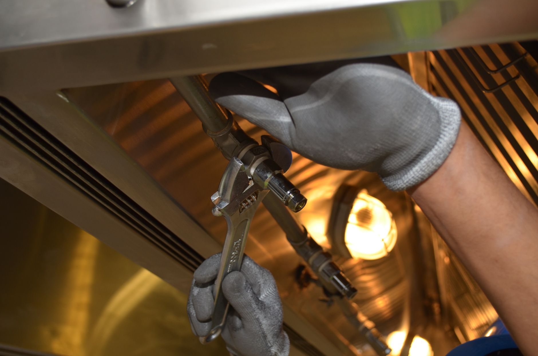 A plumber repairing a leaking pipe under a customer's kitchen sink